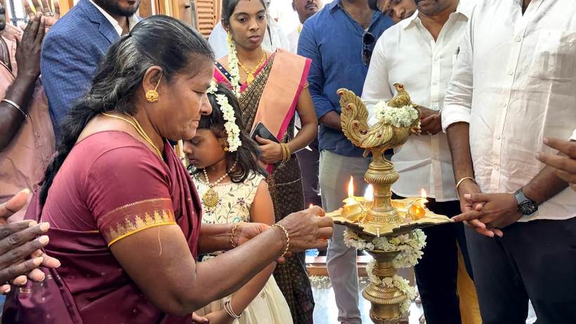 A guest lights the traditional brass lamp at a branch opening